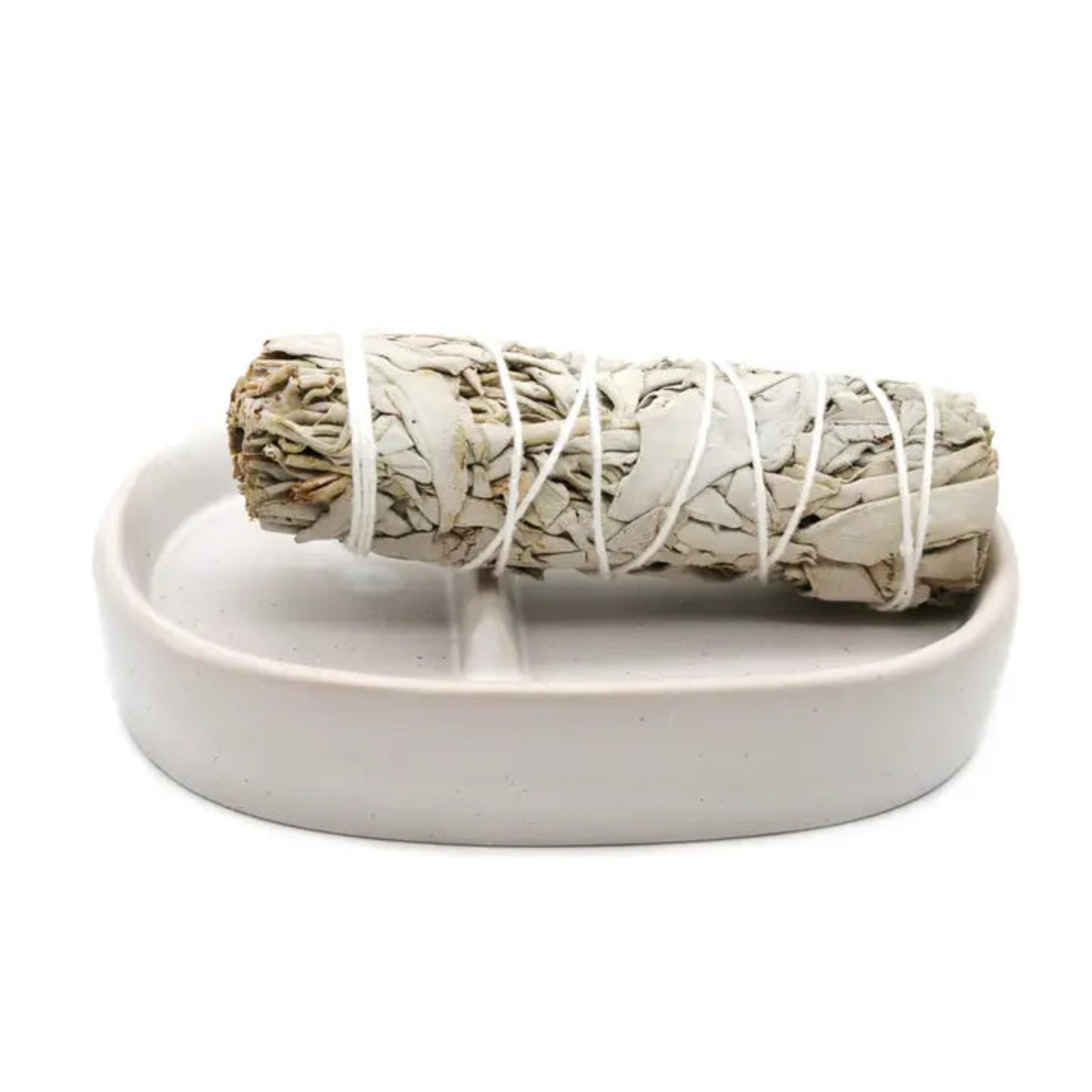Rolled sage smudge stick on a white ceramic dish with a white background